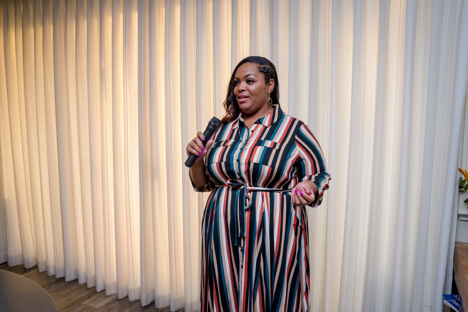 Alicia Broadway standing before a lit stage backdrop, mid-address