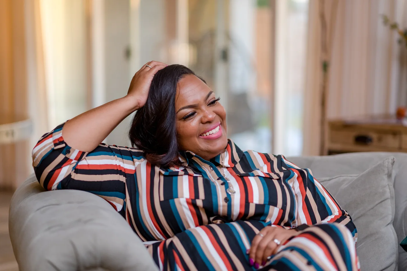 Alicia Broadway seated and laughing during a conversation at home